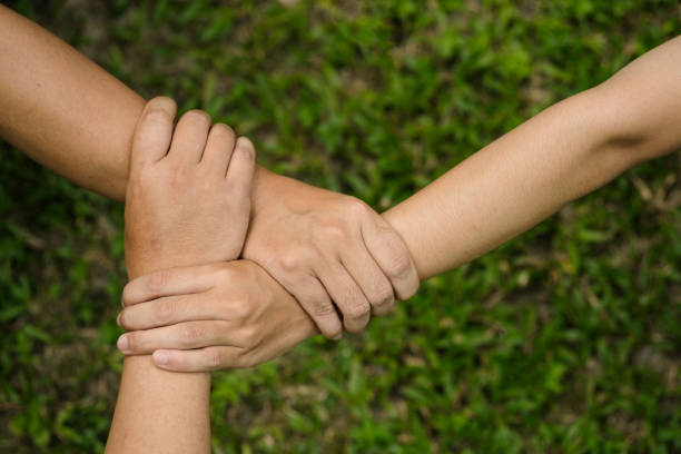 istock Hands holding tight promise mission teamwork green ecology system web banner template. Three friends partner hand mission green background triangle partnership together banner template with copy space. 1440442423