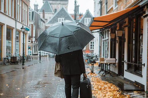 Black business man traveller commuting in Delft on a rainy day