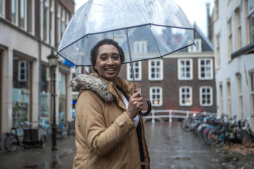 Black female business woman traveller commuting in Delft on a rainy day