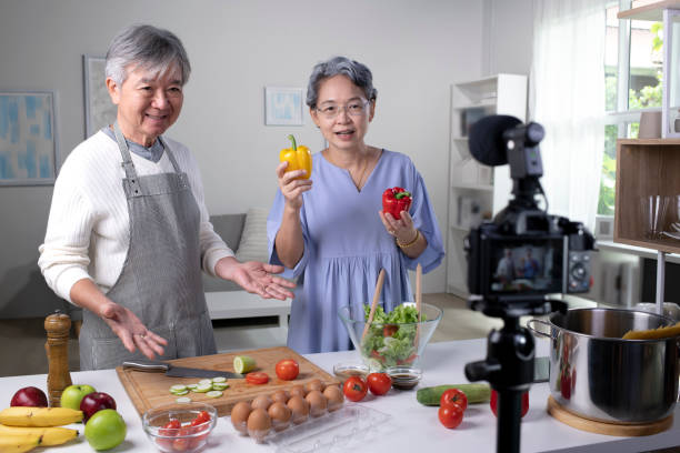 happy asian senior couple blogueur vlog et influenceur en ligne enregistrant du contenu vidéo sur les aliments sains dans la cuisine. - social networking youtube internet leisure activity photos et images de collection