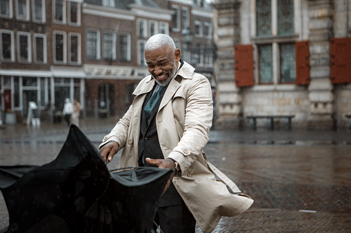 Black business man traveller struggling with his umbrella in Delft on a rainy day