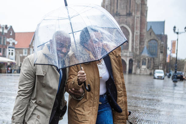 Two multi ethnic traveller colleagues commuting together in Delft on a rainy day