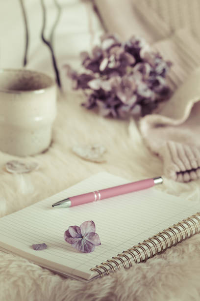 istock Cozy coffee break scene with notebook, cup and wool fabric, cream and lilac colors 1440448129