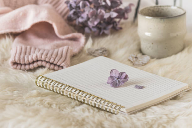 istock Cozy coffee break scene with notebook, cup and wool fabric, cream and lilac colors 1440448308