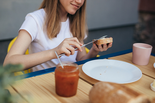 close up of teenager girl eating bread butter and jam for breakfast