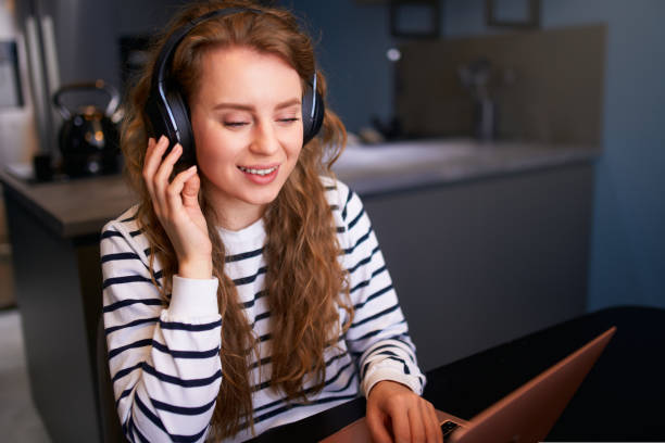 istock Customer support service call center manager speaking, working from home. Curly woman with headset, talks on video conference to laptop webcam. Young business woman consults business partners remotely 1440450553
