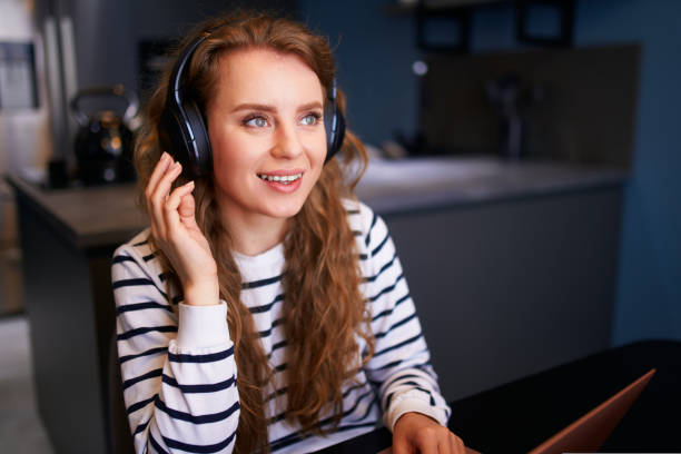 istock Customer support service call center manager speaking, working from home. Curly woman with headset enjoys listening to music. Young business woman consults business partners remotely. 1440450677