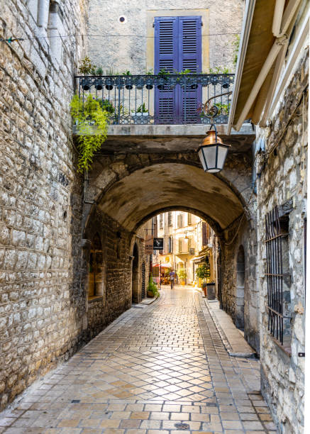 フランスの中世都市ヴァンスの旧市街にあるrue de leveche通りにあるカラフルな歴史的な家々の下にアーチが通過する狭い通り - cote de azure ストックフォトと画像