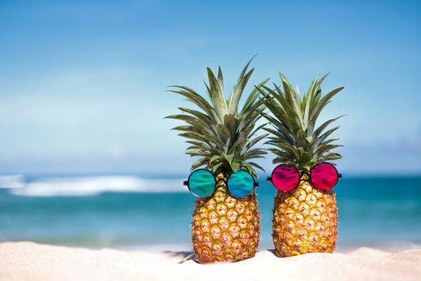 istock Creative tropical pineapple pair in sunglasses on sandy beach 1440451829
