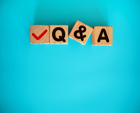 Q and A on the wooden toy blocks with letters on blue background. Concept word forming with cube on background - questions and answers