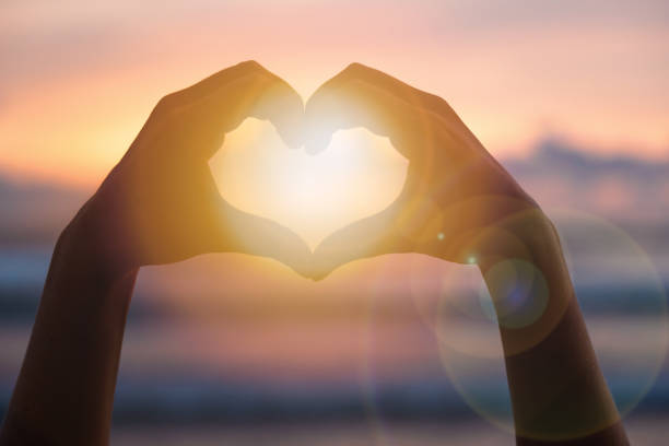 istock Hands forming a heart shape with sunset silhouette 1440453314