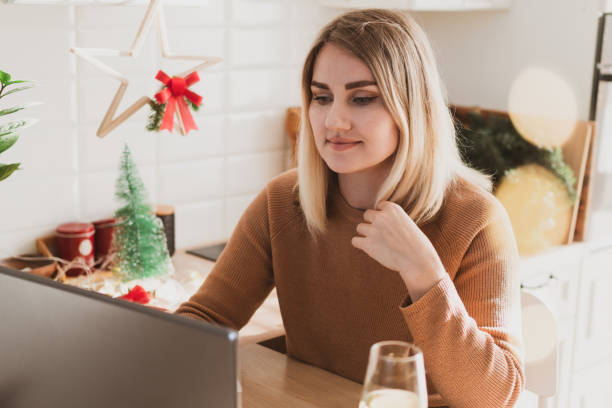 istock Attractive woman video chatting on laptop while sitting in her kitchen in festive interior 1440453321