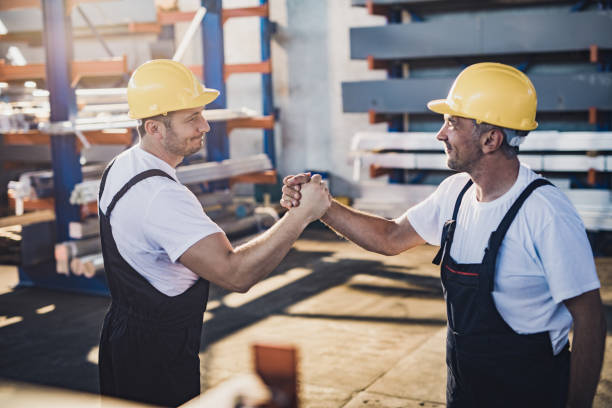 istock Happy manual workers greeting each other in aluminum mill. 1440454110