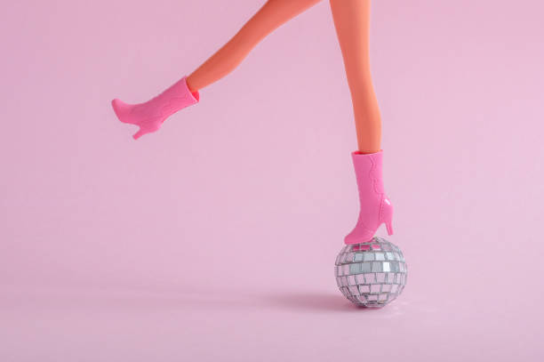 istock Doll feet on a small disco ball on a pink background 1440454525