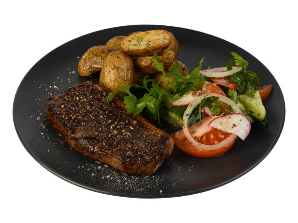 istock meat steaks, fried potato slices and vegetables on a plate, isolated white background 1440454907