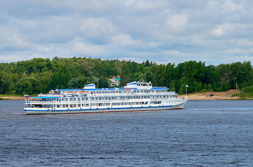River cruise ship on summer river under cloudy sky