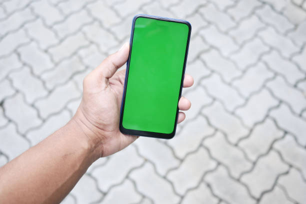 istock Close up of young man hand using smart phone with green screen 1440455391