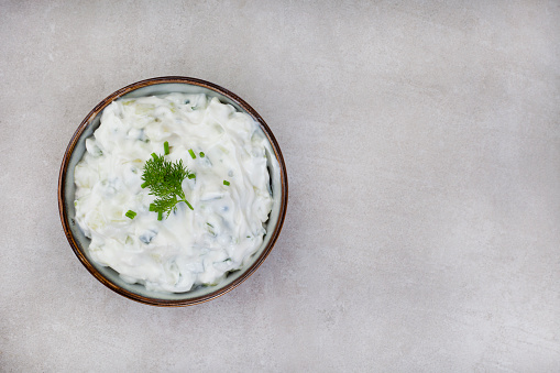 Fresh Greek favorite, Tzatziki made with cucumber, yogurt and herbs. On a mottled grey surface with copy space
