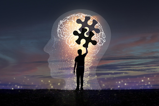 A silhouette of a young man piecing together a jigsaw puzzle. in brain icon concept Creativity and concept innovation Creative ideas for , dementia memory loss, Alzheimer's disease and concepts.