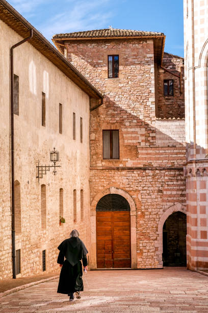 A Franciscan friar walks towards the Sacred Abbey of San Francesco in the medieval heart of Assisi in Umbria stock photo