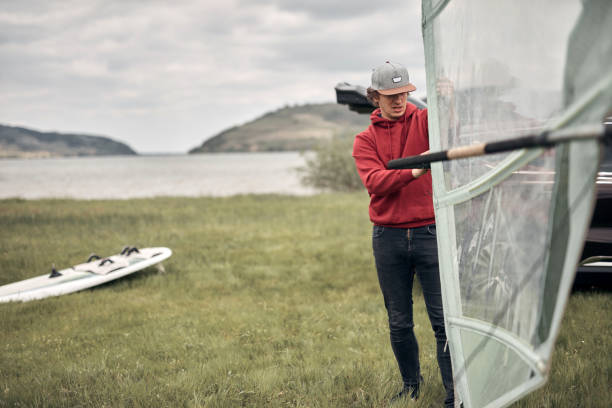 istock Windsurfer and camper packing and unpacking from a car in nature. 1440459976