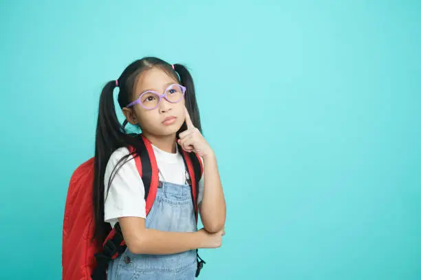 Photo of Close-up kid schoolgirl pointed cheeks and thinking.