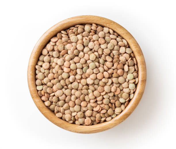 Uncooked green lentils in wooden bowl isolated on white background with clipping path Uncooked green lentils in wooden bowl isolated on white background with clipping path lentil stock pictures, royalty-free photos & images