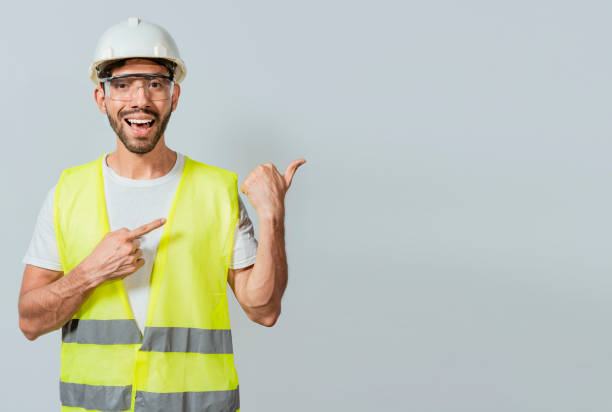 istock Construction engineer with vest pointing at an advertisement. Engineer man pointing to side. Builder engineer pointing finger to the right isolated, Portrait of engineer man pointing aside 1440462581