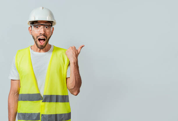 istock Surprised face construction worker pointing at an advertisement. Engineer man pointing to side. Surprised face engineer pointing finger to the right, Surprised engineer pointing to the side 1440462585
