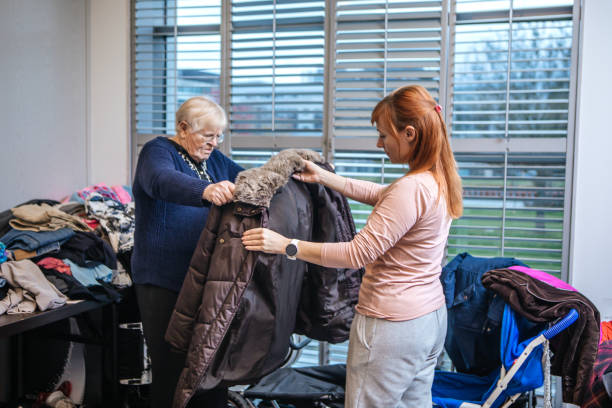 A mother and daughter refugee couple searching for clothes at a donation centre stock photo