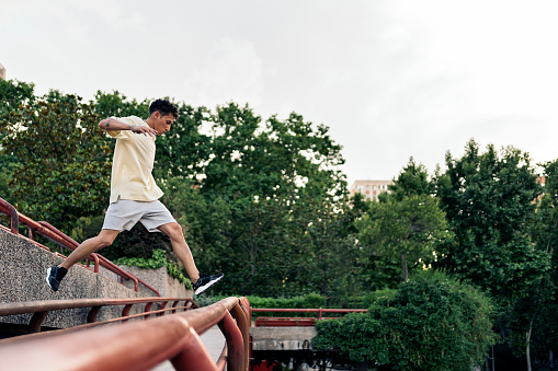 Cool young man practicing parkour in the park and having fun.