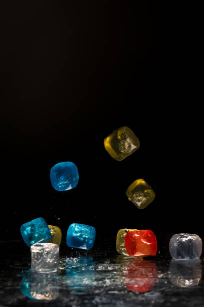 istock Falling colored cubes splashed with water on a black background. Red, yellow, blue and transparent. Conceptual, celebrated, commercial design 1440464639