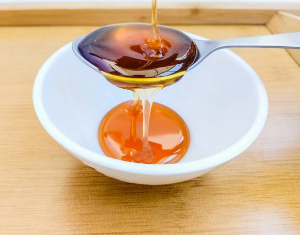 Bee honey rawhoney sweet food natural sweetener ingredient floral nectar extracted from bees hive pouring on spoon and a bowl closeup view image stock photo stock photo