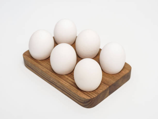 istock Fresh chicken eggs on rustic wooden rack isolated on white 1440466308