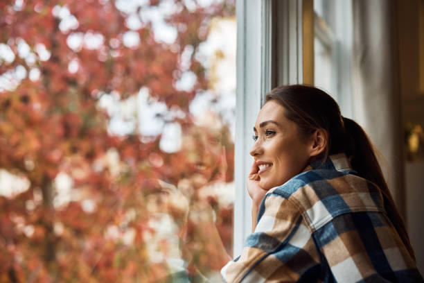 Smiling woman enjoying the view from her apartment window.