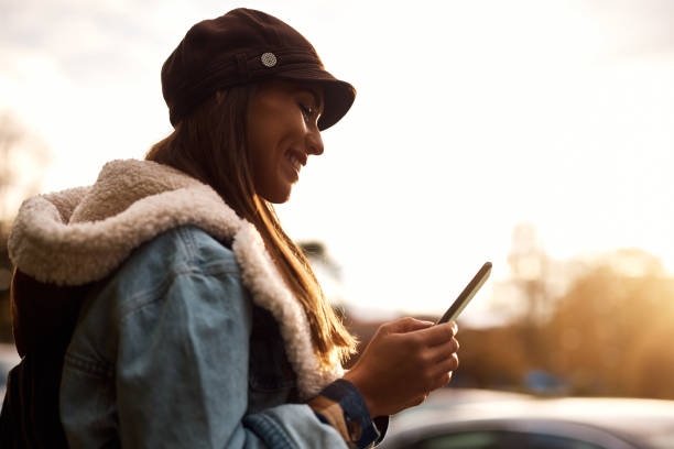 istock Young happy woman text messaging on mobile phone outdoors. 1440468492