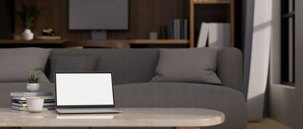 istock Laptop mockup and copy space on coffee table over blurred living room with couch in background 1440469483