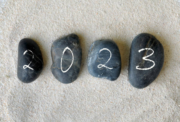 istock 2023 written on black pebbles on the sand background 1440471040