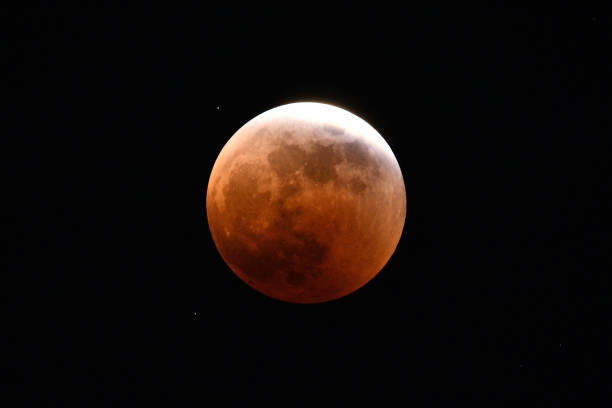 istock The moon in a total lunar eclipse, almost in the shadow of the earth. 1440471841