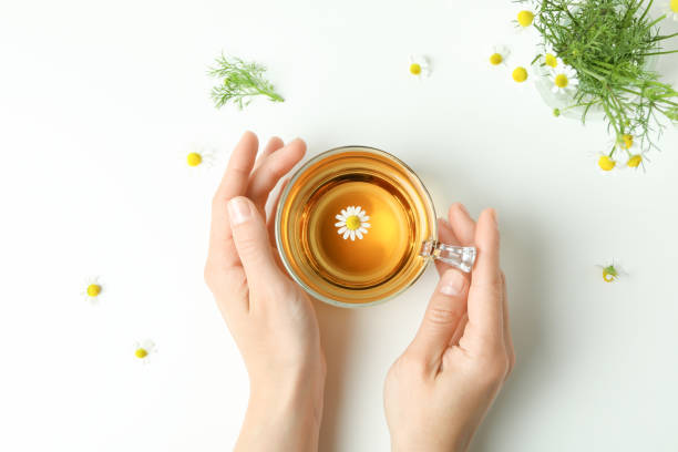 istock Female hands and chamomile tea on white background 1440473104
