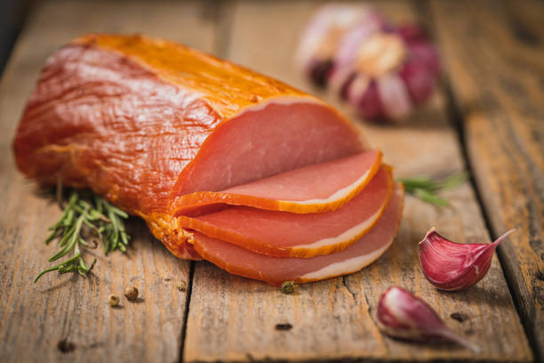 Spicy smoked ham with rosemary and kitchen knife on a table