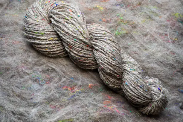Beautiful skein of colourful handdyed handspun yarn for knitting, laying on a wooden floor as a background