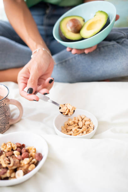 istock A woman picks up peeled peanuts with a measuring spoon. She has a split avocado in a bowl 1440480120