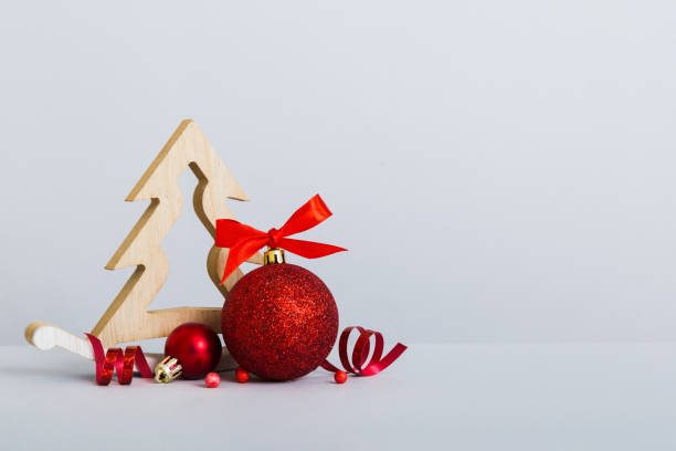 istock Christmas ball with decorative wooden tree on colored background. decoration bauble with ribbon bow with copy space 1440481517