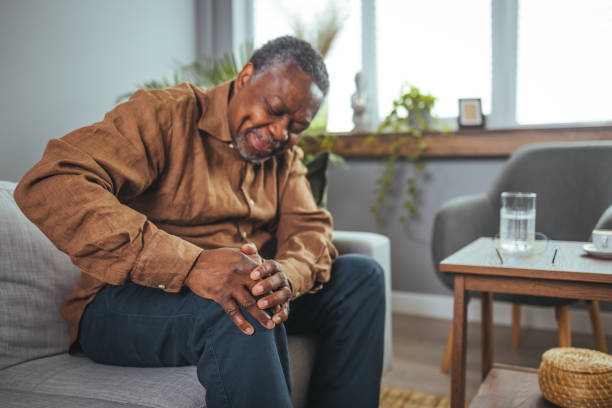 istock African mature man suffers from knee pain while sitting on a couch 1440482551