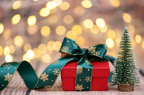 istock Christmas card with gift box and small Christmas tree on glitter background 1440484468