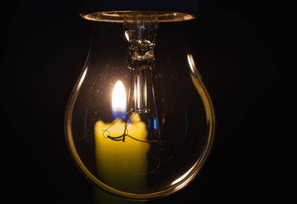 istock Light bulb with lit candle in background. Blackout city, load shedding, energy crisis or power outage, symbolic image. 1440488601
