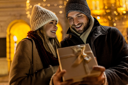 Smiling couple opening Christmas present gift box