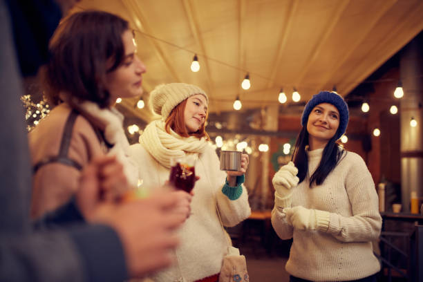 istock Group of young people spending time together, drinking mulled wine, talking, laughing at winter fair at evening time. Winter holidays, Christmas vibes concept 1440491539