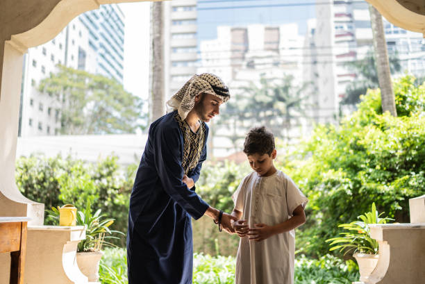 istock Young man teaching younger brother to pray 1440493580
